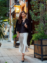 a lady wears a black tweed jacket with a beige satin skirt